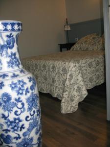 un jarrón azul y blanco sentado junto a una cama en Home Nantua studio meublés Ain-Jura, en Nantua