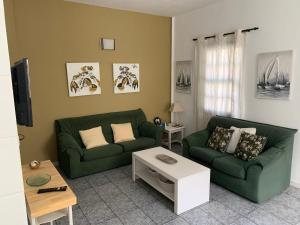 a living room with two green couches and a table at Rooftop Casa El Banco in El Charco