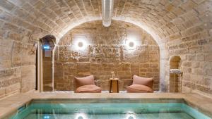 a pool in a stone building with two chairs and a table at Le Petit Beaumarchais Hotel & Spa in Paris