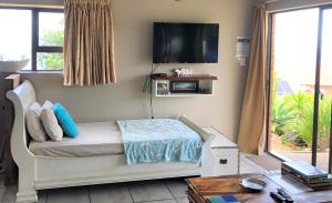 a bedroom with a bed with a tv on the wall at Wilderness Ocean View Cottage in Wilderness