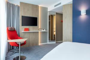 a hotel room with a red chair and a tv at Holiday Inn Express - Almere, an IHG Hotel in Almere