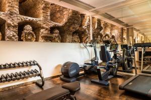 a gym with several tread machines and a wall withartifacts at Hotel Villa Carlotta in Taormina