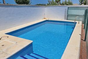 a swimming pool with blue water in front of a fence at Chalet Pinar de Roche in Conil de la Frontera