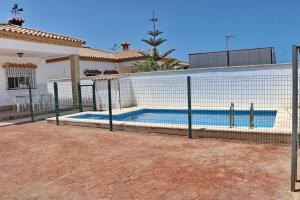 a fence around a swimming pool in front of a house at Chalet Pinar de Roche in Conil de la Frontera