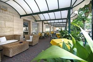 een patio met banken, tafels, stoelen en planten bij Hotel Aron in Rimini