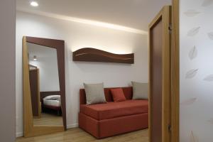 uma sala de estar com um sofá vermelho e um espelho em Monolocale Ninetta Dolomiti bellunesi em Belluno