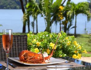 a lobster on a plate on a table with a glass of wine at Bocas del Mar in Boca Chica