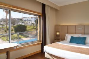 a hotel room with a bed and a large window at TRYP by Wyndham Porto Expo Hotel in Leça da Palmeira