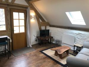 a living room with a couch and a tv at Le Séchoir in Beaulieu-sur-Dordogne