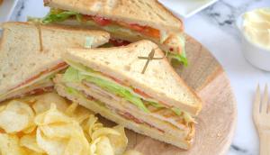 a sandwich and chips on a wooden plate at Montree Phuket Hotel in Phuket Town
