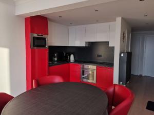 a kitchen with red cabinets and a table with red chairs at Appartement Beachview Westende in Middelkerke