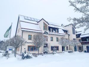 ein schneebedecktes Gebäude mit Bäumen davor in der Unterkunft Landhotel Bauernschmitt in Pottenstein