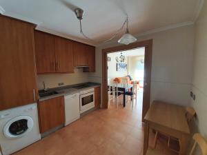 a kitchen with wooden cabinets and a table and a dining room at Apartamentos Nordés2 in Malpica