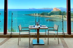 una mesa con sillas y vistas al océano en Smy Carlos V Wellness & Spa Alghero en Alghero