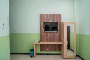 a room with a tv on a wall with a table at Urbanview Hotel de Kopen Malang by RedDoorz in Malang