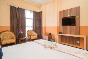 a bedroom with a bed with a television and chairs at Urbanview Hotel de Kopen Malang by RedDoorz in Malang