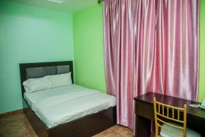 a small bedroom with a bed and a desk with a desk at Emmy Hotels & Suites in Lekki