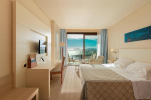 Cette chambre d'hôtel comprend un lit et un bureau avec vue. dans l'établissement Smy Carlos V Wellness & Spa Alghero, à Alghero