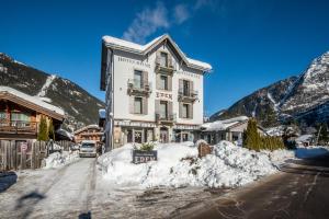 夏蒙尼-勃朗峰Eden Hotel, Apartments and Chalet Chamonix Les Praz的山前雪覆盖的街道上的建筑