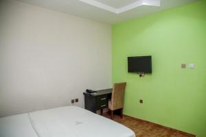 a bedroom with a bed and a desk and a tv at Emmy Hotels & Suites in Lekki