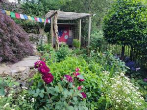 a garden with red roses and a colorful banner at Beautiful quiet room in the heart of Holmfirth in Holmfirth