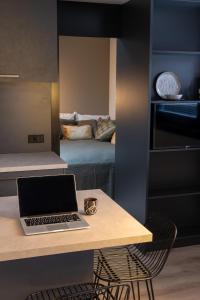City Stay&Go Enschede في أنسخديه: يوجد جهاز كمبيوتر محمول على مكتب في غرفة مع سرير