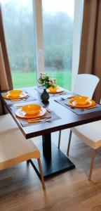 uma mesa de jantar com pratos de laranja, garfos e facas em Appartement avec piscine près de Honfleur em Équemauville