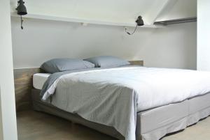 a bedroom with a bed with white sheets and blue pillows at De Heerlykheid in Nuenen