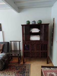 a living room with a wooden cabinet and a chair at Beautiful quiet room in the heart of Holmfirth in Holmfirth