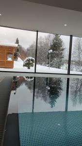 une vue d'une cour enneigée depuis une fenêtre dans l'établissement Studio 20qm mit Balkon und Innenpool - 22010, à Schluchsee