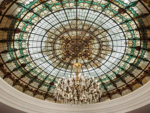 a large glass domed ceiling with a chandelier at Hotel Colón Gran Meliá - The Leading Hotels of the World in Seville