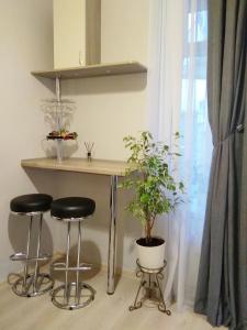 a table and two stools in a room with a plant at Comfortable modern apartment in Lviv