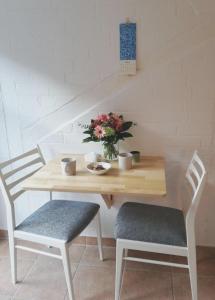 a wooden table with two chairs and a vase of flowers at Alte Stellmacherei - Ferienwohnung 2 in Riepsdorf
