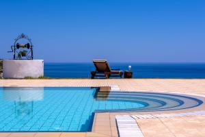 a swimming pool with a chair next to the ocean at Villa Pasithea in Faliraki