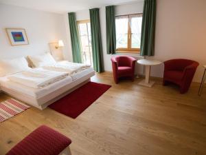 a bedroom with a white bed and two red chairs at Landhotel und Gasthof Kirchberger in Wildsteig