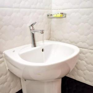a white sink in a white bathroom with a faucet at Wawa Lifestyle Regency one bedroom Apartment in Nairobi