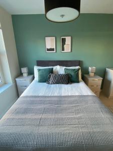 um quarto com uma grande cama branca com paredes azuis em Maltings Apartment - Spacious 2 Bed Ground Floor Apartment em Kirkcaldy