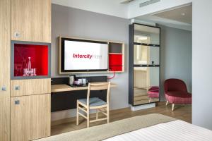 um quarto de hotel com uma secretária e uma televisão em IntercityHotel Wiesbaden em Wiesbaden