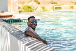a man in a swimming pool with a beer at Royal Karoo Safari Lodge in Steytlerville