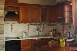 a kitchen with wooden cabinets and a table with flowers at Dolinnaya Tower in Sudak