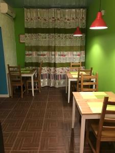 comedor con mesas, sillas y paredes verdes en Mini-Hotel Spi Zdes en Khabarovsk