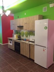Il comprend une cuisine dotée d'un réfrigérateur blanc et de murs verts. dans l'établissement Mini-Hotel Spi Zdes, à Khabarovsk