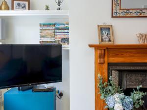 a television sitting on top of a blue cabinet next to a fireplace at Pass the Keys Cosy terrace within city walls ideal for exploring in Canterbury