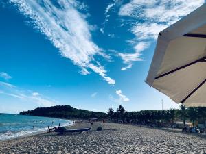 uma praia com pessoas e o oceano e um guarda-sol em Excelente Apartamento Vista Mar em Maragogi em Maragogi