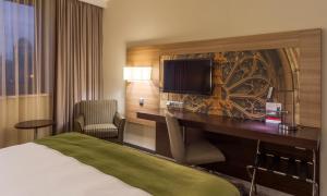 a hotel room with a bed and a desk with a television at Holiday Inn - Kyiv, an IHG Hotel in Kyiv