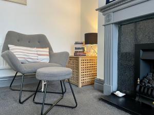 a chair and stool in a living room with a fireplace at Entire holiday home in Blackpool with free parking and a private patio garden in Blackpool