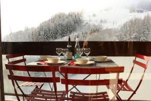a table with two chairs and wine glasses on a balcony at Appartements Immeuble Zodiaque in Le Corbier