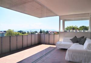 1 dormitorio con sofá blanco en el balcón en Cocoon am See en Lochau