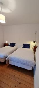 Duas camas num quarto com paredes brancas e pisos em madeira em Le Venec, Lopérec, France em Lopérec