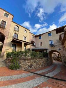 a large building with a stone walkway in front of it at Rokkaria Holidays Apartments in Villasimius